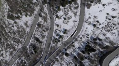 Ağaçlı, yollu ve arabalı karlı bir arazinin insansız hava aracı görüntüleri.