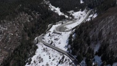 Manzaralı İHA görüntüleri. Yolları ve arabaları olan karlı bir orman 