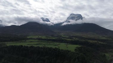Yavaş uçan dron görkemli dağları ve bulutlu gökyüzünü kaydediyor. 