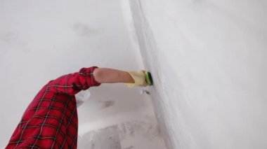 Kırmızı gömlekli yüz maskesi takan ve yenileme dairesinde duvarları yıkayan bir kadın. Yavaş çekim videosu.