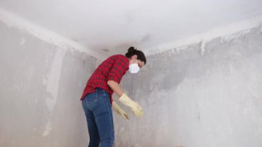 Kırmızı gömlekli kadın maske takıyor, yeni bir dairede tavan yıkıyor. 