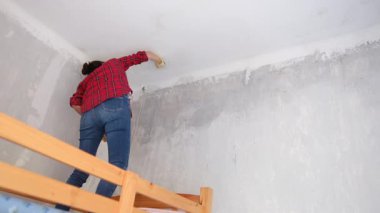 Kırmızı gömlekli kadın maske takıyor, yeni bir dairede tavan yıkıyor. 