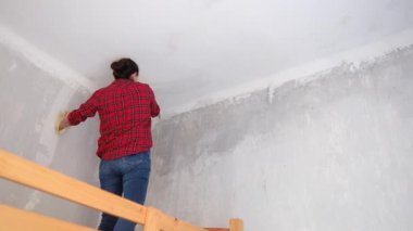 Kırmızı gömlekli kadın maske takıyor, yeni bir dairede tavan yıkıyor. 