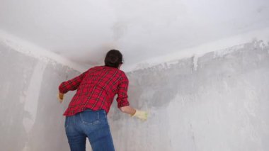 Kırmızı gömlekli kadın maske takıyor, yeni bir dairede tavan yıkıyor. 