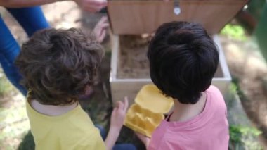 İki küçük çocuk ve annelerinin tavuk kümesinde yumurta topladığı ağır çekim videoları. 