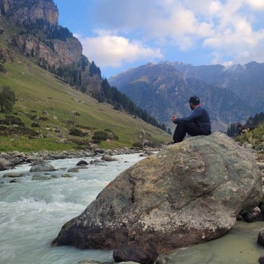 Bir dağ nehrinde ceketli bir adam duruyor..