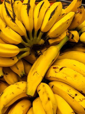 A bunch of vibrant yellow bananas, ready to eat. The image highlights the texture and inviting color of the fruits, ideal for projects related to healthy eating, markets and tropical cuisine. clipart