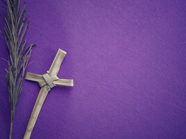 İyi Cuma, Paskalya ve Kutsal Hafta konsepti. Kuru bir palmiye yaprağının arka planı ve bulanık mor arka planda palmiye yaprağından yapılmış bir Kutsal Haç..