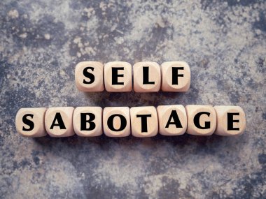 Sosyal mesele ve davranış sorunu kavramı. SELF SABOTAGE tahta bloklara yazılmış. Bulanık stil arkaplanlı.