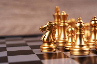 Motivasyon işi ve yönetim kavramı. Satranç tahtasına yerleştirilmiş altın satranç taşları. Bulanık biçimlendirilmiş arkaplan.