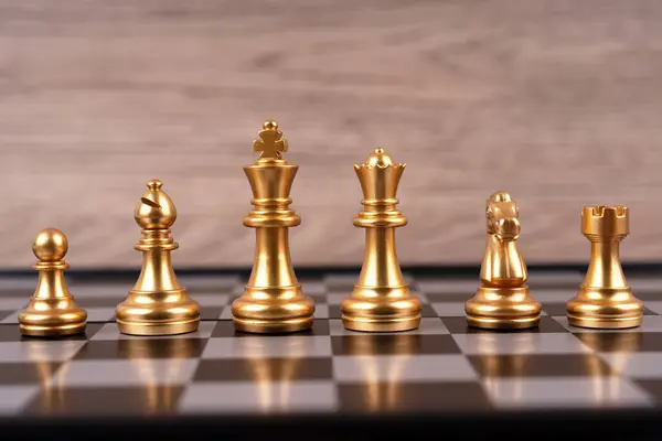 Motivational business and management concept. Golden chess pieces placed on a chessboard. Blurred styled background.
