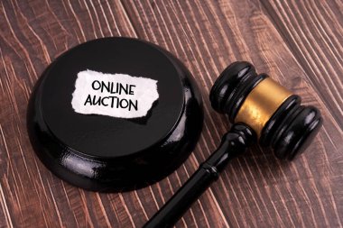 Tahta tokmak ve üzerinde ONLINE Açık Artırması yazan bir kağıt parçası.