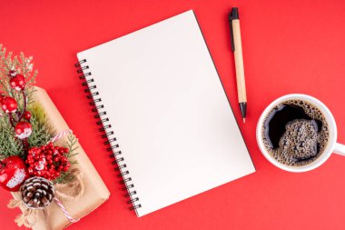 Noel süslemeleri ve kırmızı arka planda fotokopi alanı için boş defter. Noel konsepti.