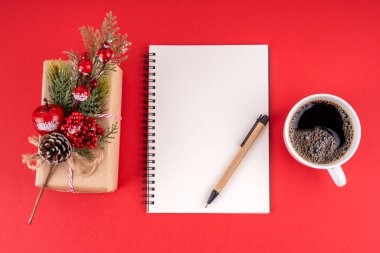 Noel süslemeleri ve kırmızı arka planda fotokopi alanı için boş defter. Noel konsepti.