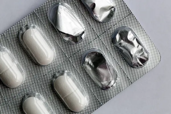 No logo white tablets. Different pills can be used in healthcare to treat different diseases and symptoms like allergies, infections and pain. Closeup color image.