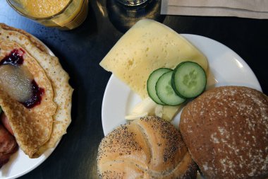 Peynirli, yeşillikli ve tereyağlı beyaz tabakta kahvaltı ekmeği. Siyah arka plan. İsveç kahvaltısı, lezzetli ve sağlıklı. Kapatma rengi resmi.