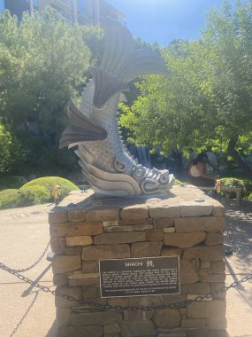 Güneşli bir günde bol yeşillikli göl manzarası. Mavi bir gökyüzü ve arka planda binalar vardı..