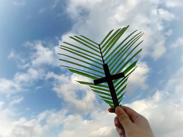 Lent,Holy Week,Palm Sunday and Good Friday concepts - heart shaped of palm leaf and wooden cross with sky background.