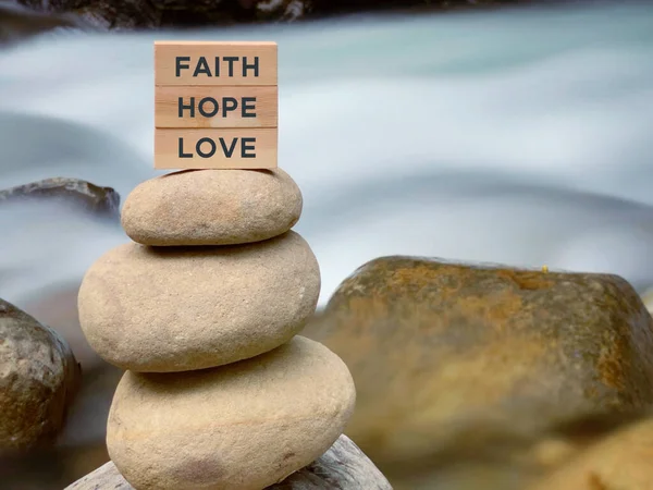 Faith hope love text on wooden blocks with nature background.