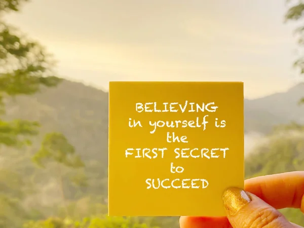 Inspirational and motivational quote of believing in yourself is the first secret to success. Text written on yellow paper background. Stock photo.