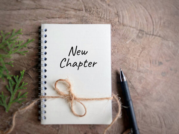 New chapter written on book in vintage background.