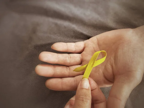 Kutlama Günü Konsepti. El altyapısı olan sarı kurdele. Dünyanın intiharı önleme gününü sembolize ediyor. Stok fotoğrafı.