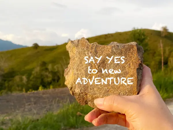 Hayat ve seyahat ilham verici bir alıntı - Yeni maceraya evet de. Kayanın üzerine elle yazılmış bir metin..
