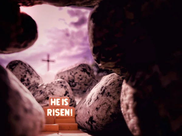Lent, Holy Week, Good Friday, Easter Sunday Concept - HE IS RISEN text with Jesus Christ empty tomb, grave of resurrection with blurry cross shape background. Stock photo