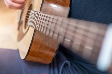 Erkek elleri akustik gitar çalıyor, yakın çekim. Akustik gitar ve güzel bir ahşap. .