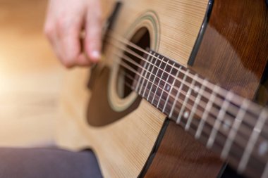 Erkek elleri akustik gitar çalıyor, yakın çekim. Akustik gitar ve güzel bir ahşap. .