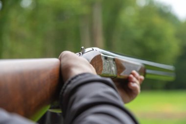 Skeet Atıcılık. Güneşli bir günde atış poligonunda atış talimi yapan bir adam. Tek başına, kendinden emin, yetenekli ve deneyimli. Atış ve Silahlar.