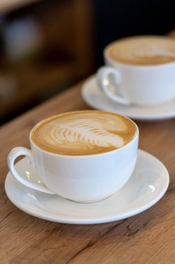 Bir kafedeki masada kapuçino. Bir fincan latte, ahşap bir masada kahve..