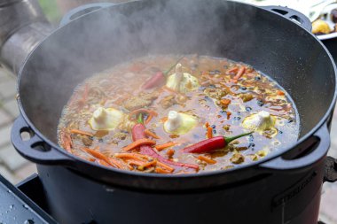 Dev bir kazanda gerçek Özbek pilavı. Özbekistan 'da milli yemekleri pişirmek. Kazanda etli pilav var. Geleneksel pilav pişirme