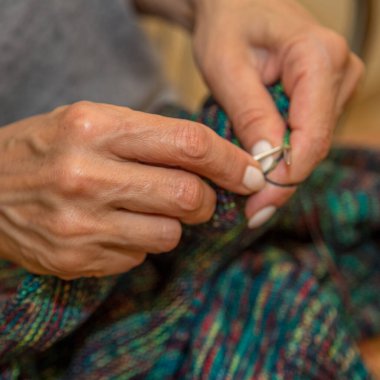 Yün ipliği kullanarak telli el yapımı giysiler ören tanınmamış bir kadının ellerine yakın durun. Boş zaman etkinliği kavramı. İplikten örgü örmek..