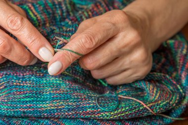 Yün ipliği kullanarak telli el yapımı giysiler ören tanınmamış bir kadının ellerine yakın durun. Boş zaman etkinliği kavramı. İplikten örgü örmek..