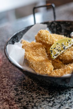 Beyaz soslu tavuk nugget. Lezzetli bir hamurun içine yerleştirilmiş, Panko ile çıtır çıtır olmuş ve masanın üstündeki tabağa yakın sosa sarılmış tavuk külçeleri..