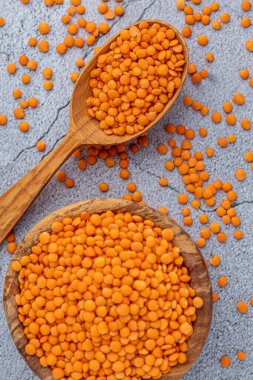 Ahşap arka planda ahşap ölçü kabıyla ahşap kasede kırmızı mercimek fotoğrafı. Sağlıklı bir yaşam tarzı. Vejetaryen ve vejetaryen diyeti.