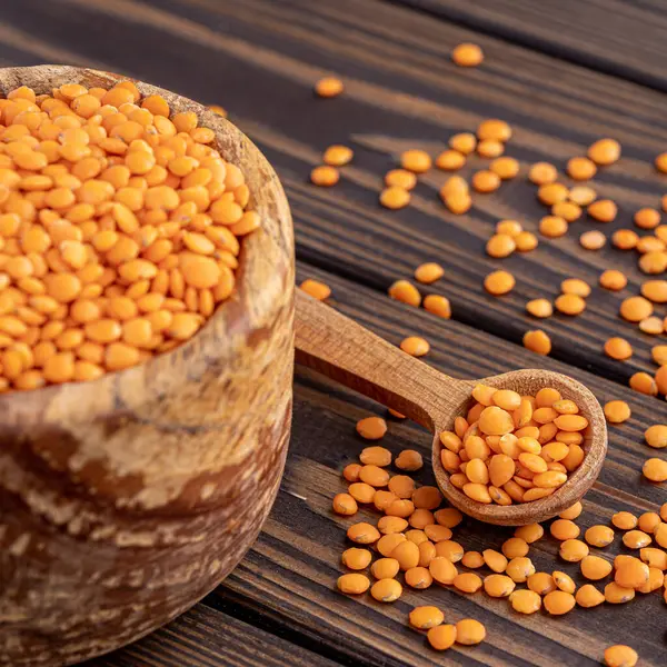 stock image Photo of red lentils in wooden bowl with wooden measuring cup on wooden background.  Healthy lifestyle. Vegetarian and vegan diet.