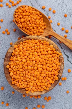 Ahşap arka planda ahşap ölçü kabıyla ahşap kasede kırmızı mercimek fotoğrafı. Sağlıklı bir yaşam tarzı. Vejetaryen ve vejetaryen diyeti.