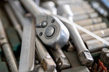 Her erkeğin garajındaki farklı araçların ve parçaların yakın çekim fotoğrafları. Otomobil kontrolü ve araba servisi konsepti. Atölyenin duvarında farklı aletler, özellikle anahtarlar asılı..