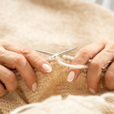 Yün ipliği kullanarak telli el yapımı giysiler ören tanınmamış bir kadının ellerine yakın durun. Boş zaman etkinliği kavramı. İplikten örgü örmek..