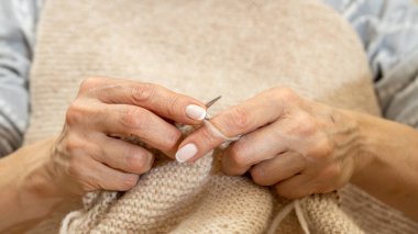 Yün ipliği kullanarak telli el yapımı giysiler ören tanınmamış bir kadının ellerine yakın durun. Boş zaman etkinliği kavramı. İplikten örgü örmek..