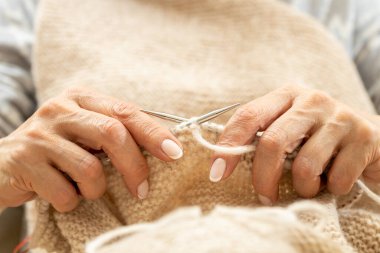 Yün ipliği kullanarak telli el yapımı giysiler ören tanınmamış bir kadının ellerine yakın durun. Boş zaman etkinliği kavramı. İplikten örgü örmek..
