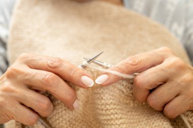 Yün ipliği kullanarak telli el yapımı giysiler ören tanınmamış bir kadının ellerine yakın durun. Boş zaman etkinliği kavramı. İplikten örgü örmek..