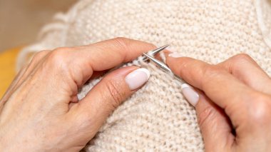 Yün ipliği kullanarak telli el yapımı giysiler ören tanınmamış bir kadının ellerine yakın durun. Boş zaman etkinliği kavramı. İplikten örgü örmek..