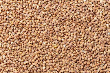 Buckwheat Grains on Plate on Wooden Background, Top View, Copy Space.Hulled kernels of buckwheat grains close up. Food background. clipart