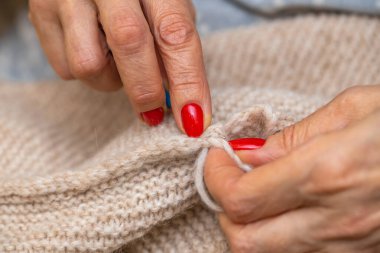 Yün ipliği kullanarak telli el yapımı giysiler ören tanınmamış bir kadının ellerine yakın durun. Boş zaman etkinliği kavramı. İplikten örgü örmek..