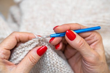 Yün ipliği kullanarak telli el yapımı giysiler ören tanınmamış bir kadının ellerine yakın durun. Boş zaman etkinliği kavramı. İplikten örgü örmek..