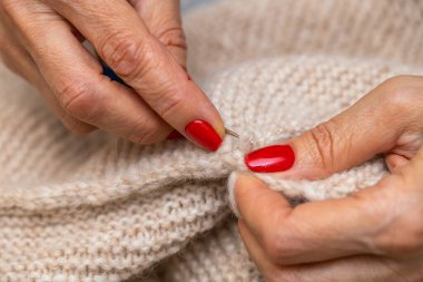Yün ipliği kullanarak telli el yapımı giysiler ören tanınmamış bir kadının ellerine yakın durun. Boş zaman etkinliği kavramı. İplikten örgü örmek..
