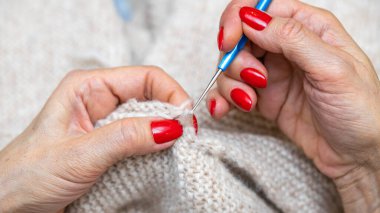 Yün ipliği kullanarak telli el yapımı giysiler ören tanınmamış bir kadının ellerine yakın durun. Boş zaman etkinliği kavramı. İplikten örgü örmek..